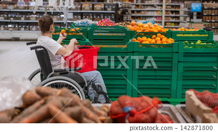A Caucasian woman in a wheelchair buys fruit at a supermarket. 142871800