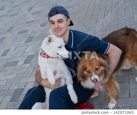 A man hugs his two dogs while on a walk. A man hugs his two dogs while on a walk. 142871863