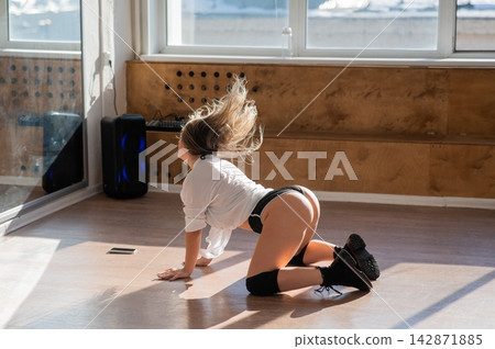 A young woman dances twerk in short shorts on the floor. A young woman dances twerk in short shorts on the floor. 142871885