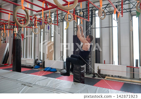 An athletic man practices at a ninja club's indoor obstacle course. An athletic man practices at a ninja club's indoor obstacle course. 142871923