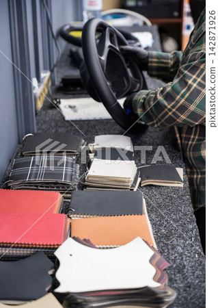 The mechanic changes the cover on the car steering wheel. The mechanic changes the cover on the car steering wheel. 142871926