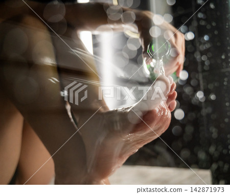 Foot fetish. A woman pours beer from a bottle onto her toes. Foot fetish. A woman pours beer from a bottle onto her toes. 142871973