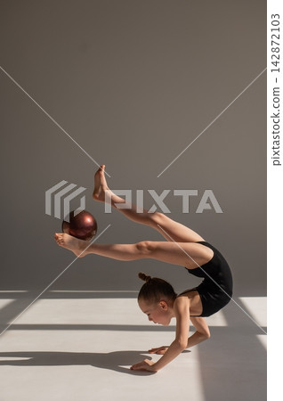 Little gymnast posing with a ball on a white background. Little gymnast posing with a ball on a white background. 142872103