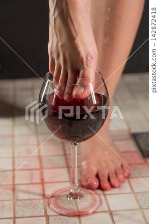 Foot fetish. A woman dips her toes in a glass of red wine. 142872418