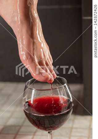 Foot fetish. A woman dips her toes in a glass of red wine. Foot fetish. A woman dips her toes in a glass of red wine. 142872426