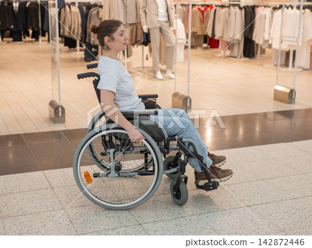 A Caucasian woman in a wheelchair shopping at a mall. A Caucasian woman in a wheelchair shopping at a mall. 142872446