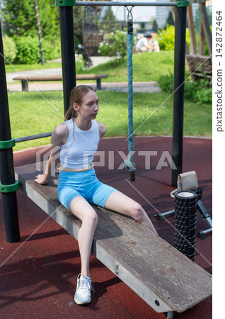 Caucasian woman on incline bench for abdominal muscles at sports ground. Caucasian woman on incline bench for abdominal muscles at sports ground. 142872464