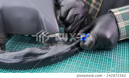 The mechanic changes the cover on the car steering wheel. The mechanic changes the cover on the car steering wheel. 142872562