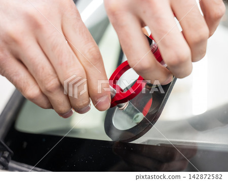 A technician injects resin into a windshield crack. A technician injects resin into a windshield crack. 142872582