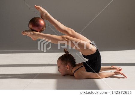 Little gymnast posing with a ball on a white background. Little gymnast posing with a ball on a white background. 142872635