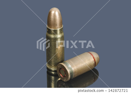 Pistol cartridges of caliber 7.62 mm and 9 mm on gray background 142872721