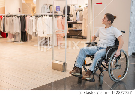 A Caucasian woman in a wheelchair shopping at a mall. A Caucasian woman in a wheelchair shopping at a mall. 142872737