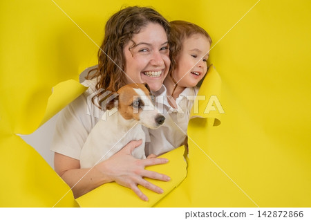 Caucasian little boy, his mother and Jack Russell Terrier dog tearing yellow paper background. Caucasian little boy, his mother and Jack Russell Terrier dog tearing yellow paper background. 142872866