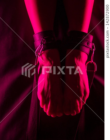 Women's legs in leather shackles. BDSM fetish. 142872900