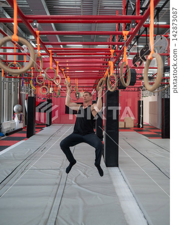 An athletic man practices at a ninja club's indoor obstacle course. An athletic man practices at a ninja club's indoor obstacle course. 142873087