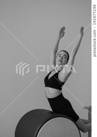 Woman practicing pilates on wooden ladder barrel machine in studio Woman practicing pilates on wooden ladder barrel machine in studio 142873198