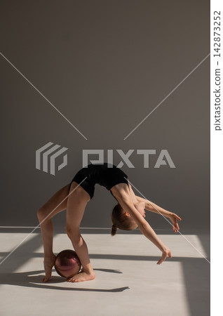 Little gymnast posing with a ball on a white background. Little gymnast posing with a ball on a white background. 142873252