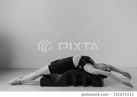 Black and white Pilates barrel exercise young woman core strength balance form Black and white Pilates barrel exercise young woman core strength balance form 142873312