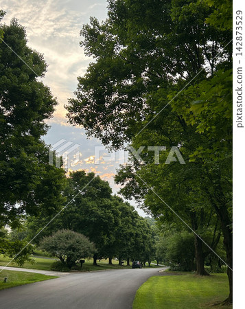 Sunset clouds over a tree-lined suburban street in Pennsylvania Sunset clouds over a tree-lined suburban street in Pennsylvania 142873529