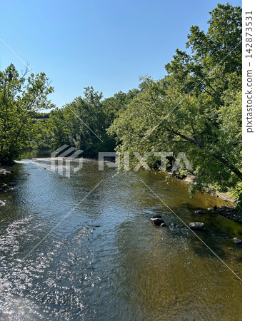 Sunlit Cuyahoga River flowing through forest in Ohio Sunlit Cuyahoga River flowing through forest in Ohio 142873531