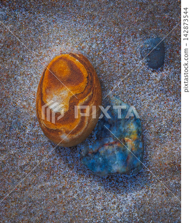 Top view of colorful pebbles on sand Top view of colorful pebbles on sand 142873544