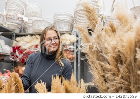 A Caucasian woman buys dried flowers at a home decor store. 142873559