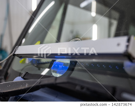 Windshield chip repair. A UV lamp dries the resin in the crack. Windshield chip repair. A UV lamp dries the resin in the crack. 142873674