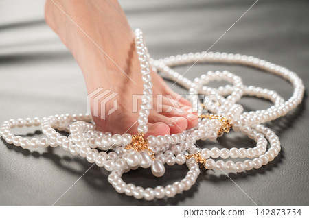 Foot fetish. Bare female feet with pearl beads. Foot fetish. Bare female feet with pearl beads. 142873754