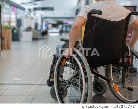 A Caucasian woman in a wheelchair shopping at a mall. A Caucasian woman in a wheelchair shopping at a mall. 142873778