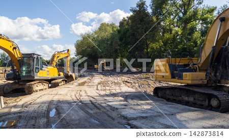 Yellow excavators are clearing the site for future construction. Yellow excavators are clearing the site for future construction. 142873814