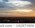 Serene sunset sky with golden cloud layer over city skyline creates peaceful evening atmosphere across vast urban landscape panorama 142873906
