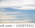 Peaceful sky background with soft white cloud layers in calm blue atmosphere filled with daylight creating serene natural mood 142873912