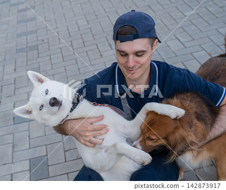 A man hugs his two dogs while on a walk.  142873917