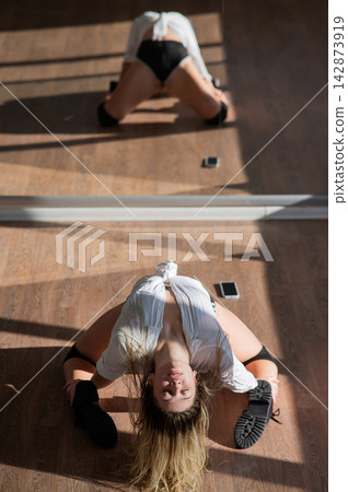 A young woman dances twerk in short shorts in front of a mirror. A young woman dances twerk in short shorts in front of a mirror. 142873919