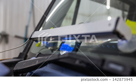 Windshield chip repair. A UV lamp dries the resin in the crack. Windshield chip repair. A UV lamp dries the resin in the crack. 142873945