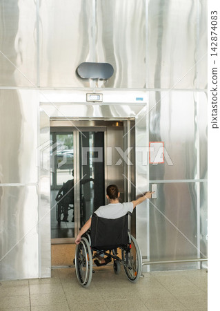 A Caucasian woman in a wheelchair uses an elevator. A Caucasian woman in a wheelchair uses an elevator. 142874083