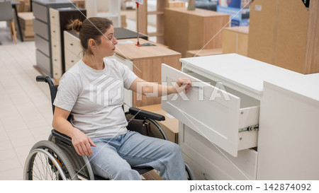 A Caucasian woman in a wheelchair buys furniture. A Caucasian woman in a wheelchair buys furniture. 142874092