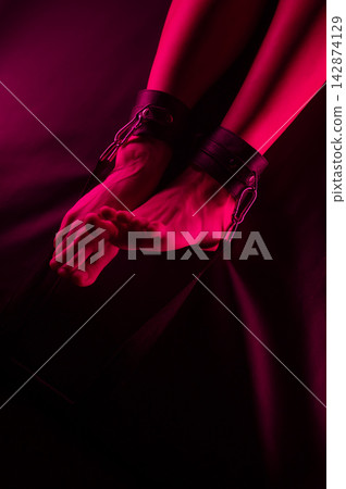 Women's legs in leather shackles. BDSM fetish. Women's legs in leather shackles. BDSM fetish. 142874129