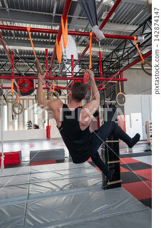 An athletic man practices at a ninja club's indoor obstacle course. An athletic man practices at a ninja club's indoor obstacle course. 142874147