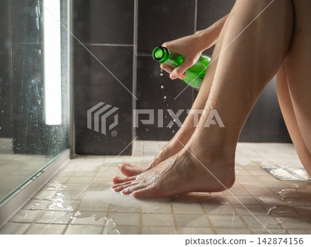 Foot fetish. A woman pours beer from a bottle onto her toes. Foot fetish. A woman pours beer from a bottle onto her toes. 142874156
