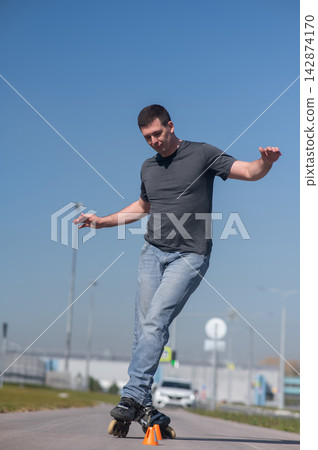 A Caucasian man rollerblades around the slalom course. A Caucasian man rollerblades around the slalom course. 142874170