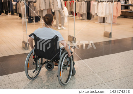 A Caucasian woman in a wheelchair shopping at a mall. A Caucasian woman in a wheelchair shopping at a mall. 142874238