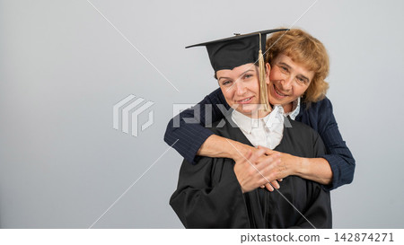 Portrait of Caucasian woman in graduation gown with her mother. Portrait of Caucasian woman in graduation gown with her mother. 142874271