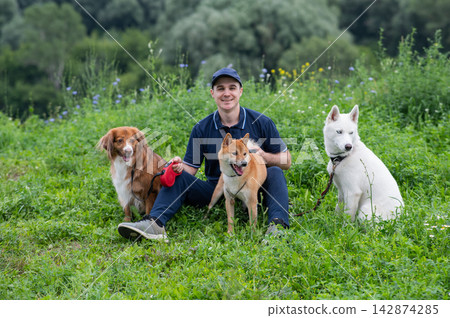 A Caucasian man walks with three dogs. Dog walker. A Caucasian man walks with three dogs. Dog walker. 142874285