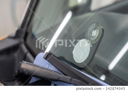 Repairing a chip on a car windshield.  142874343