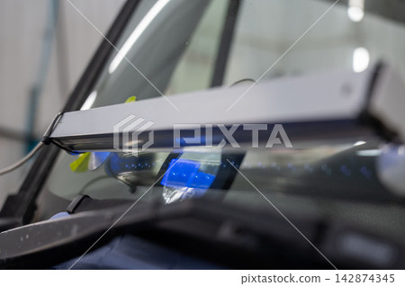 Windshield chip repair. A UV lamp dries the resin in the crack. Windshield chip repair. A UV lamp dries the resin in the crack. 142874345