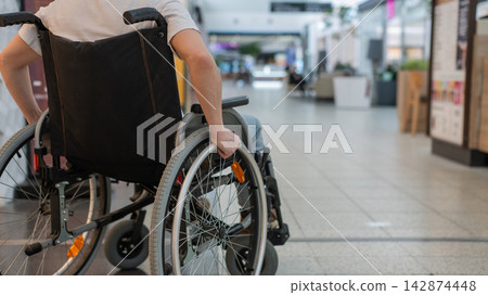 A Caucasian woman in a wheelchair shopping at a mall. A Caucasian woman in a wheelchair shopping at a mall. 142874448