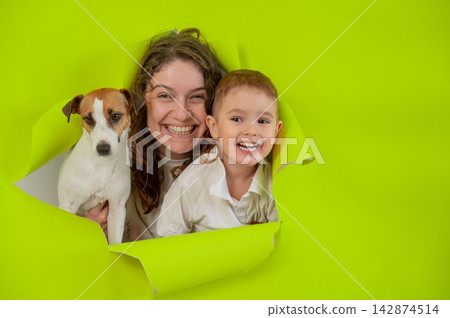 Caucasian little boy, his mother and Jack Russell Terrier dog tearing yellow paper background. Caucasian little boy, his mother and Jack Russell Terrier dog tearing yellow paper background. 142874514