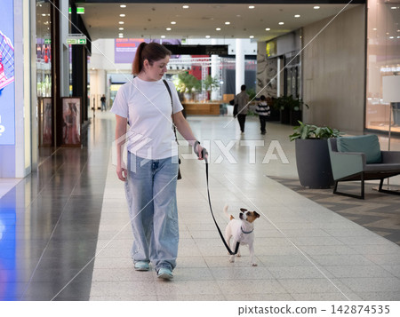Caucasian woman in a shopping mall with a Jack Russell Terrier dog.  142874535