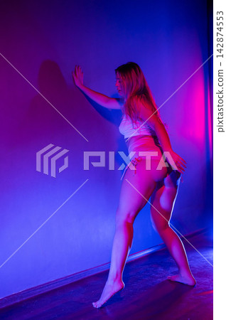 Young woman twerking in neon light. Young woman twerking in neon light. 142874553